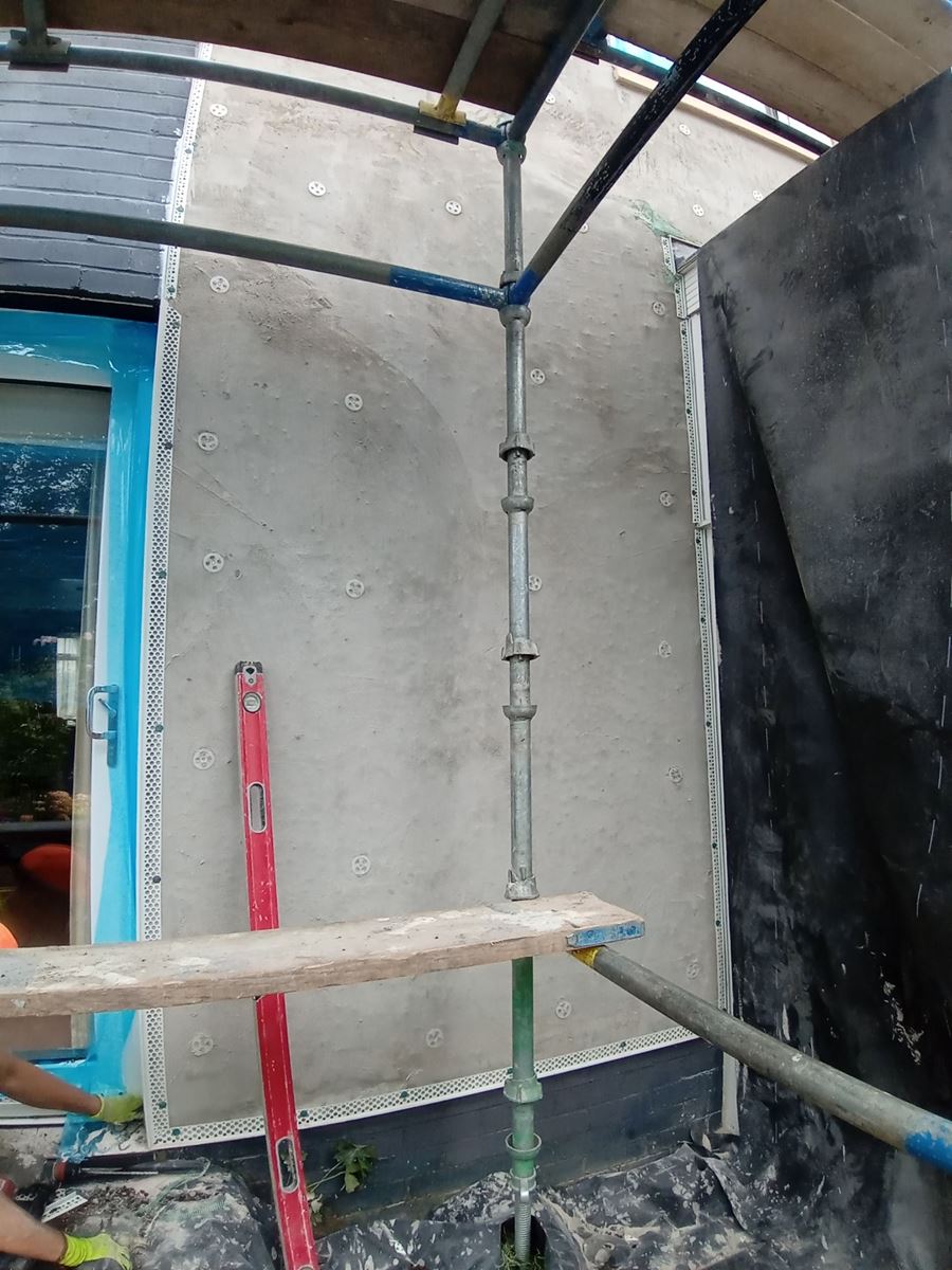roughcast render applied to the wall near scaffolding