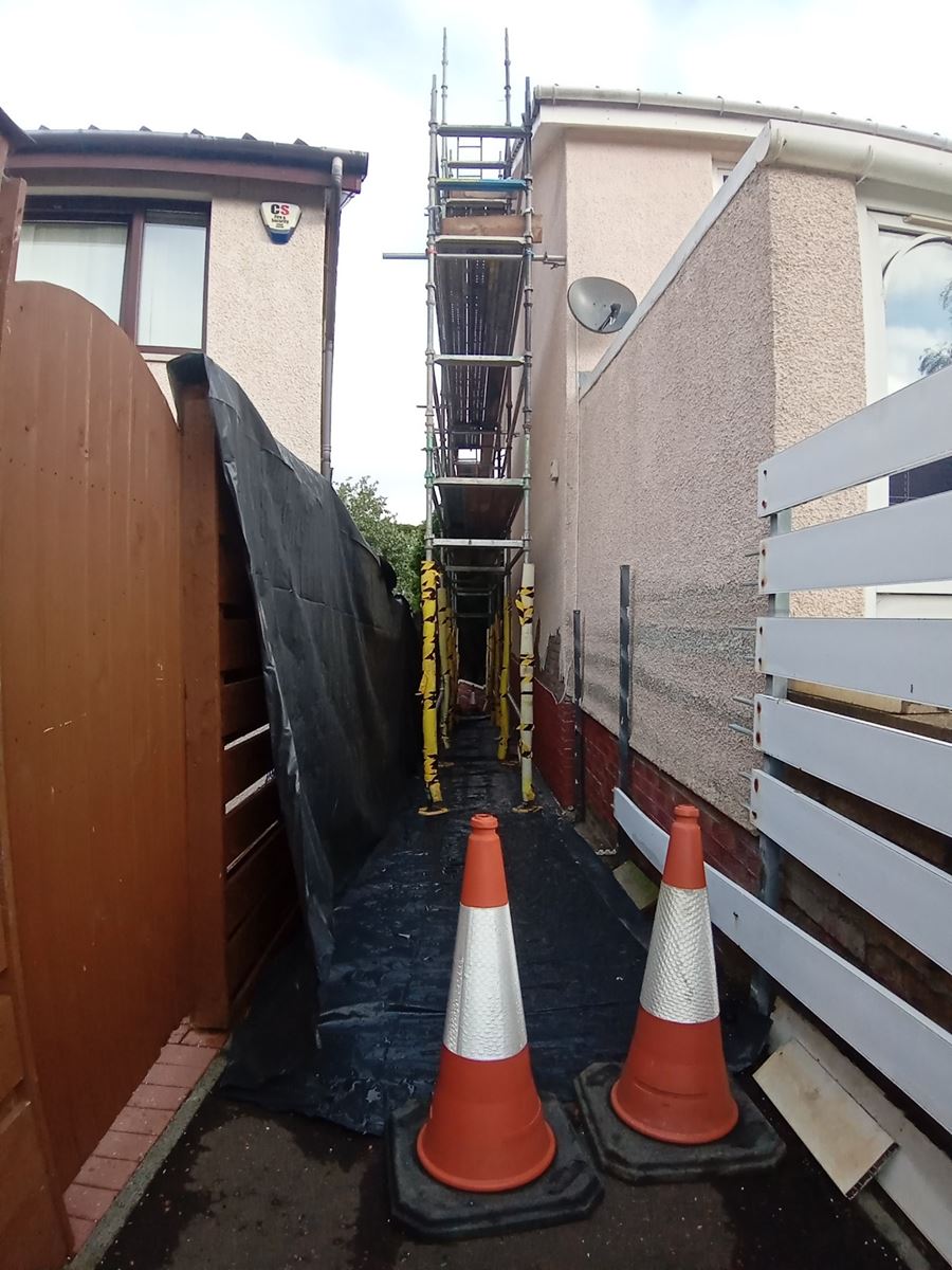 roughcast render on the side of a house with scaffolding around the area