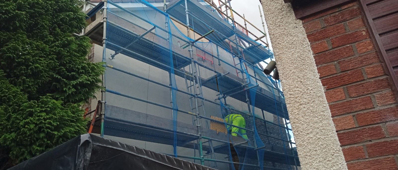 rendering Edinburgh on a house wall with tools and scaffolding visible