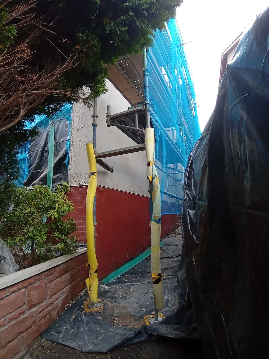 roughcast render applied near a wall with scaffolding and equipment