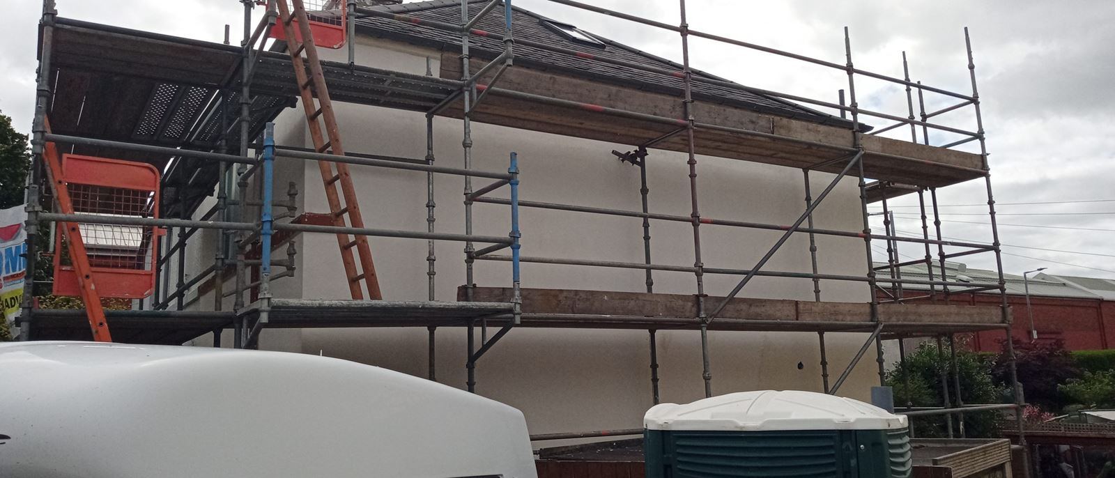 roughcast render repair on a building's exterior with tools visible