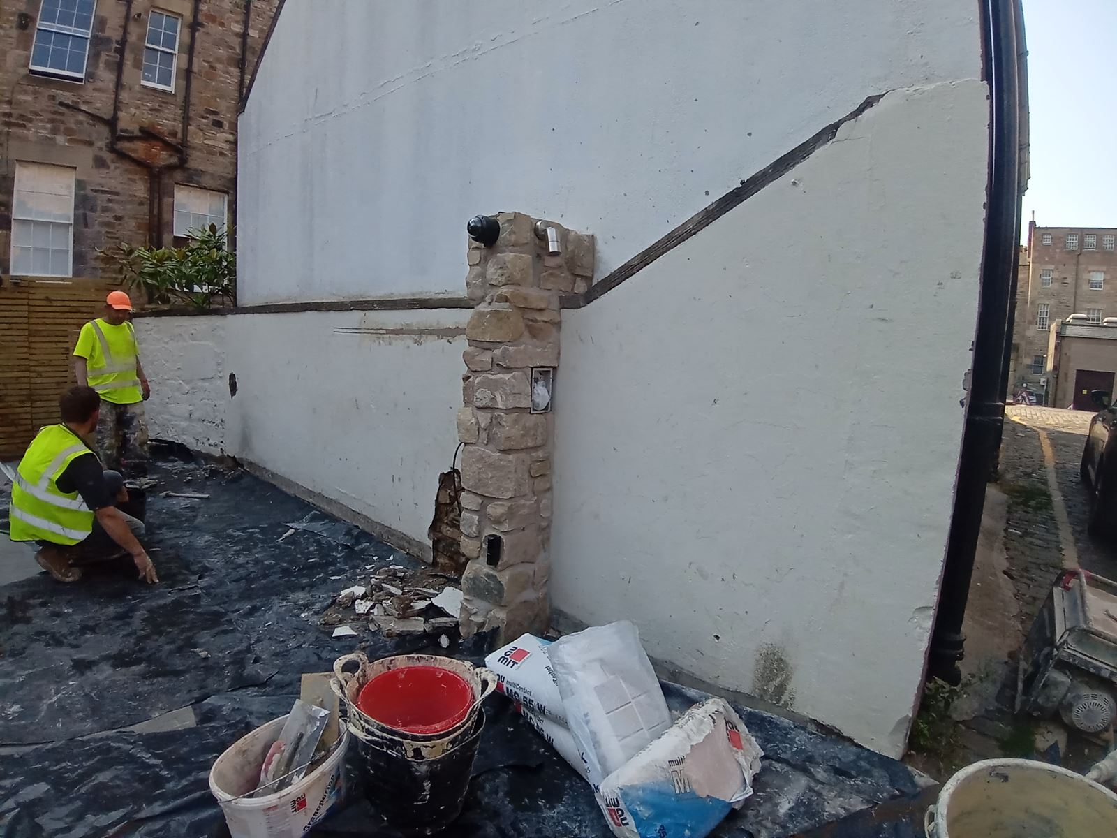 roughcasting Edinburgh on a wall with scaffolding and tools nearby