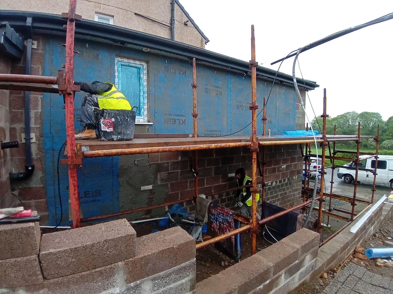roughcaster Edinburgh applying render on wall behind scaffolding