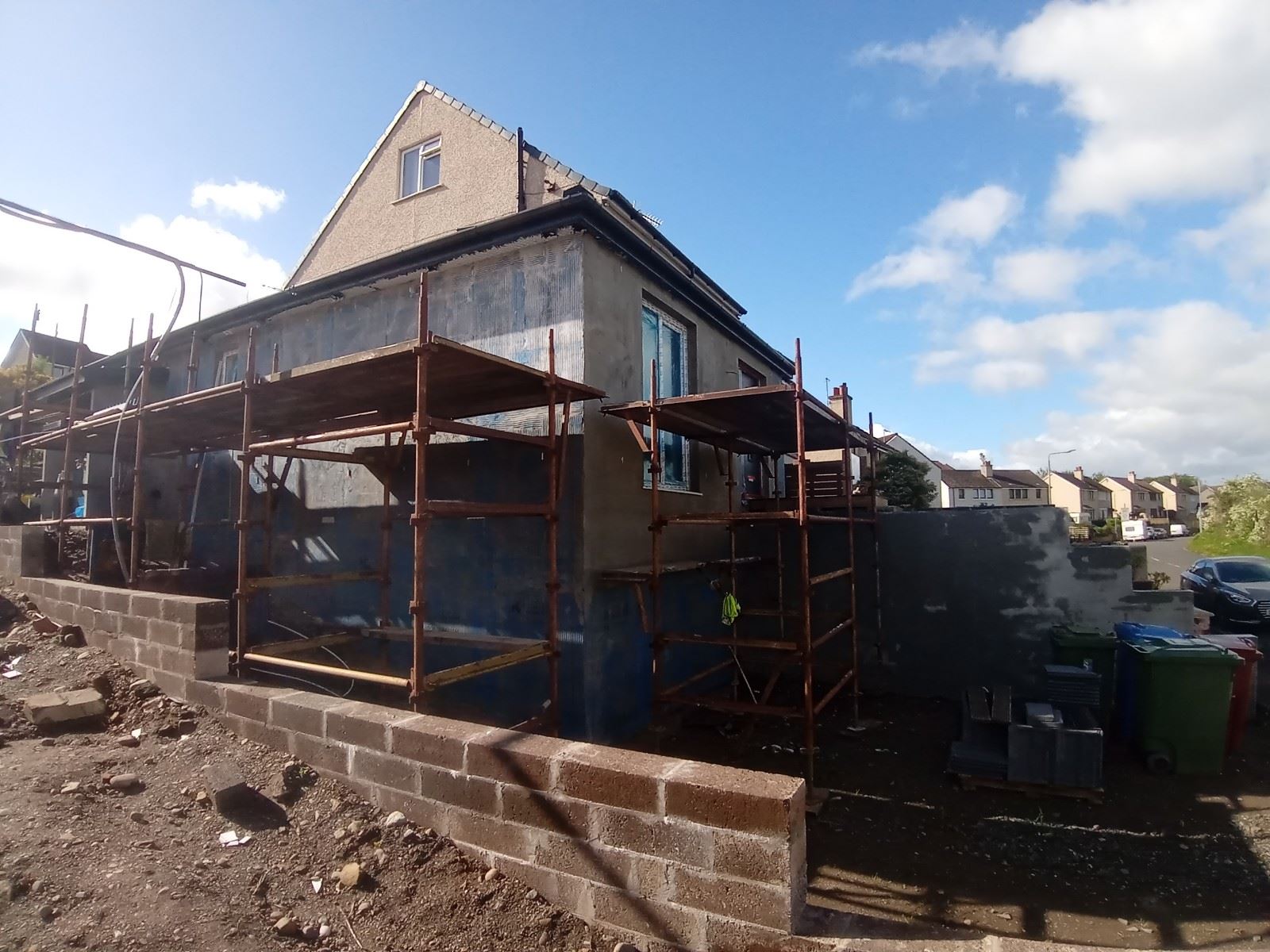 roughcast render repair on scaffolded rear façade with protective sheeting