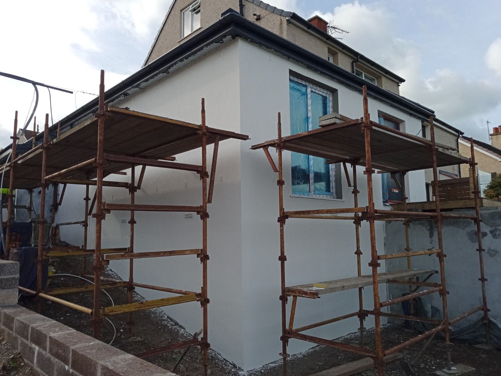 roughcast repair on sunlit white façade during renovation