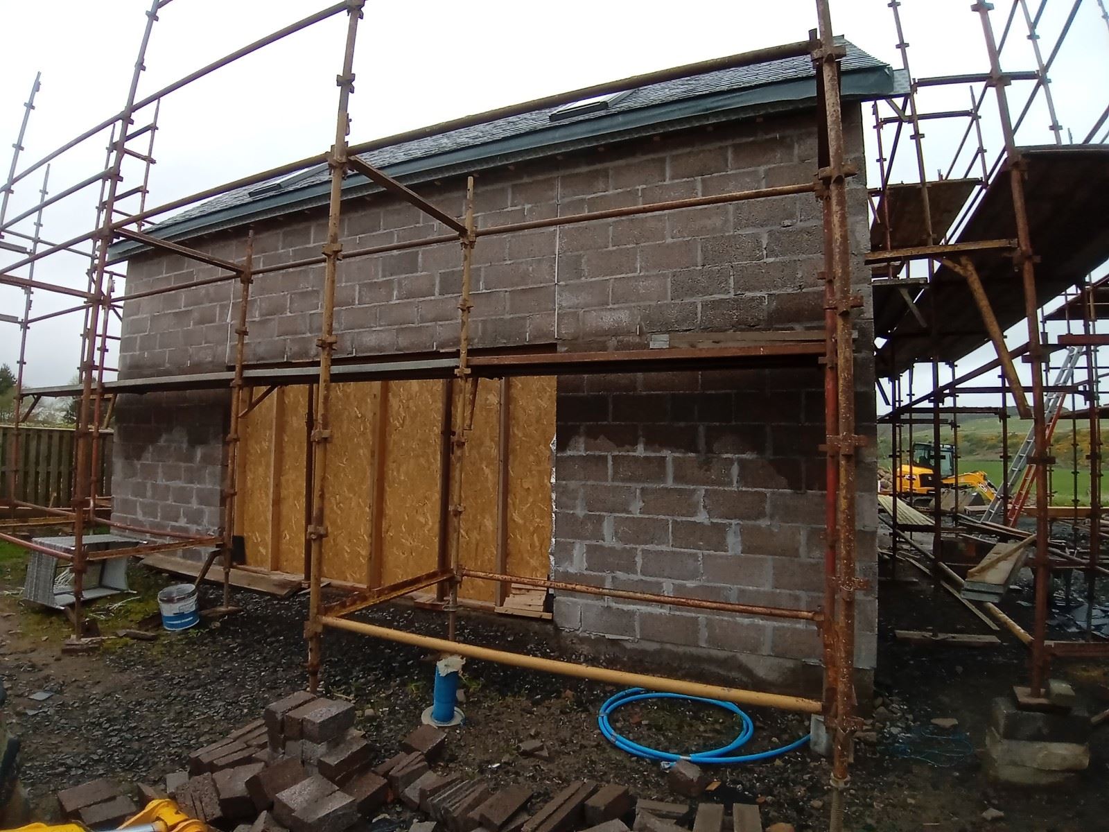 roughcast render repair on back wall with wooden boarded openings