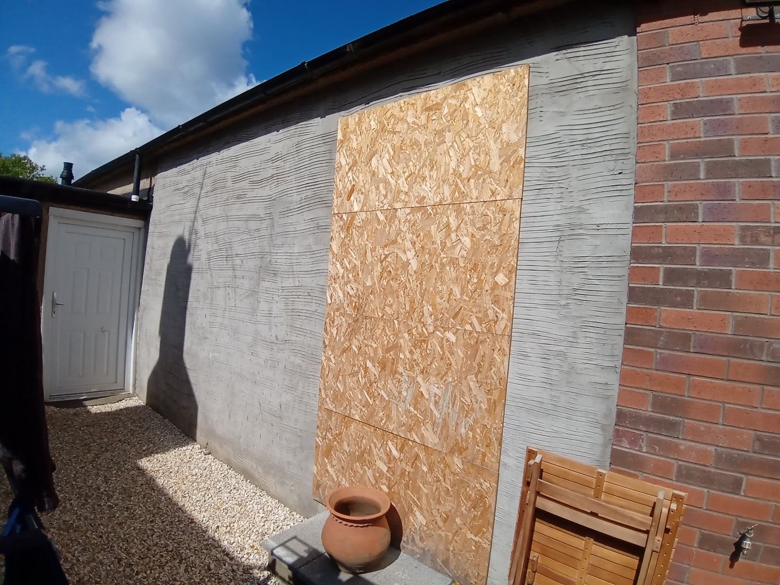 roughcast render repair on side wall with boarded windows