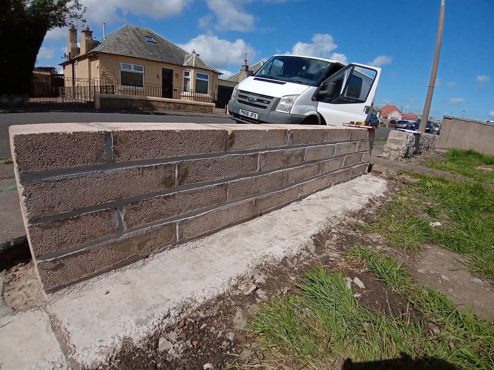 roughcast render repair on boundary base wall beside driveway