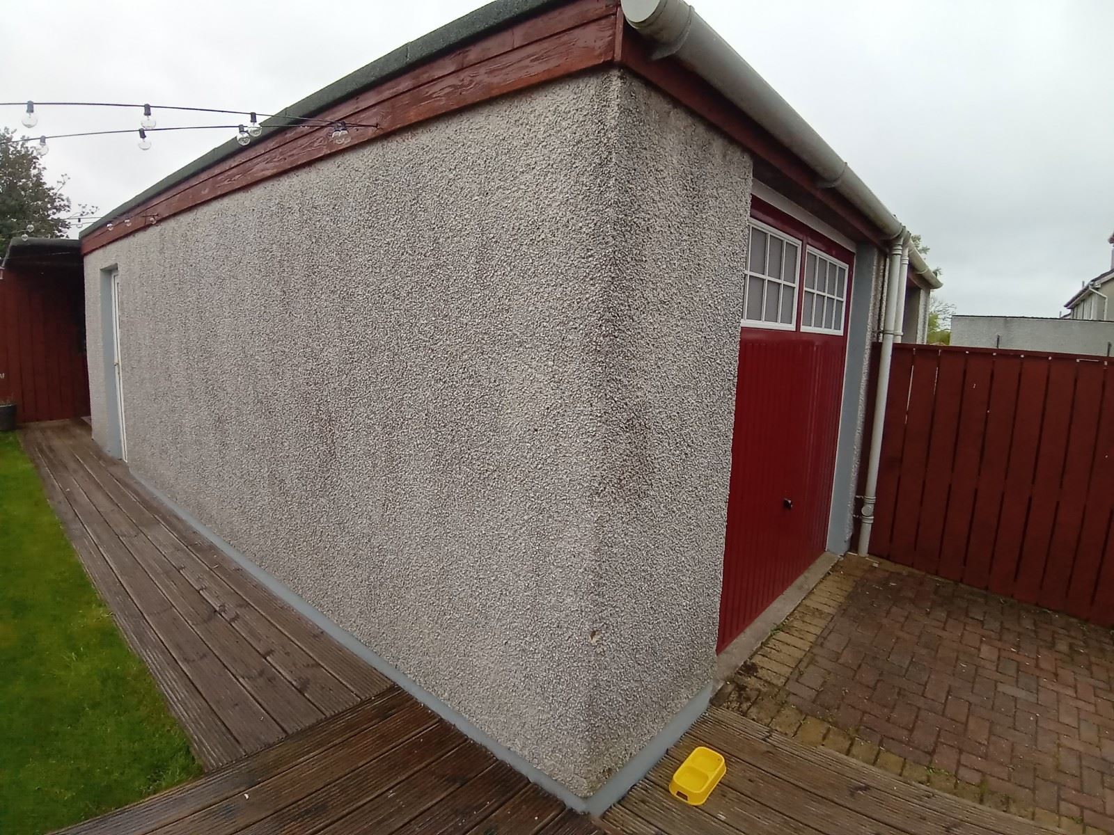 roughcast render repair on garage wall with red door