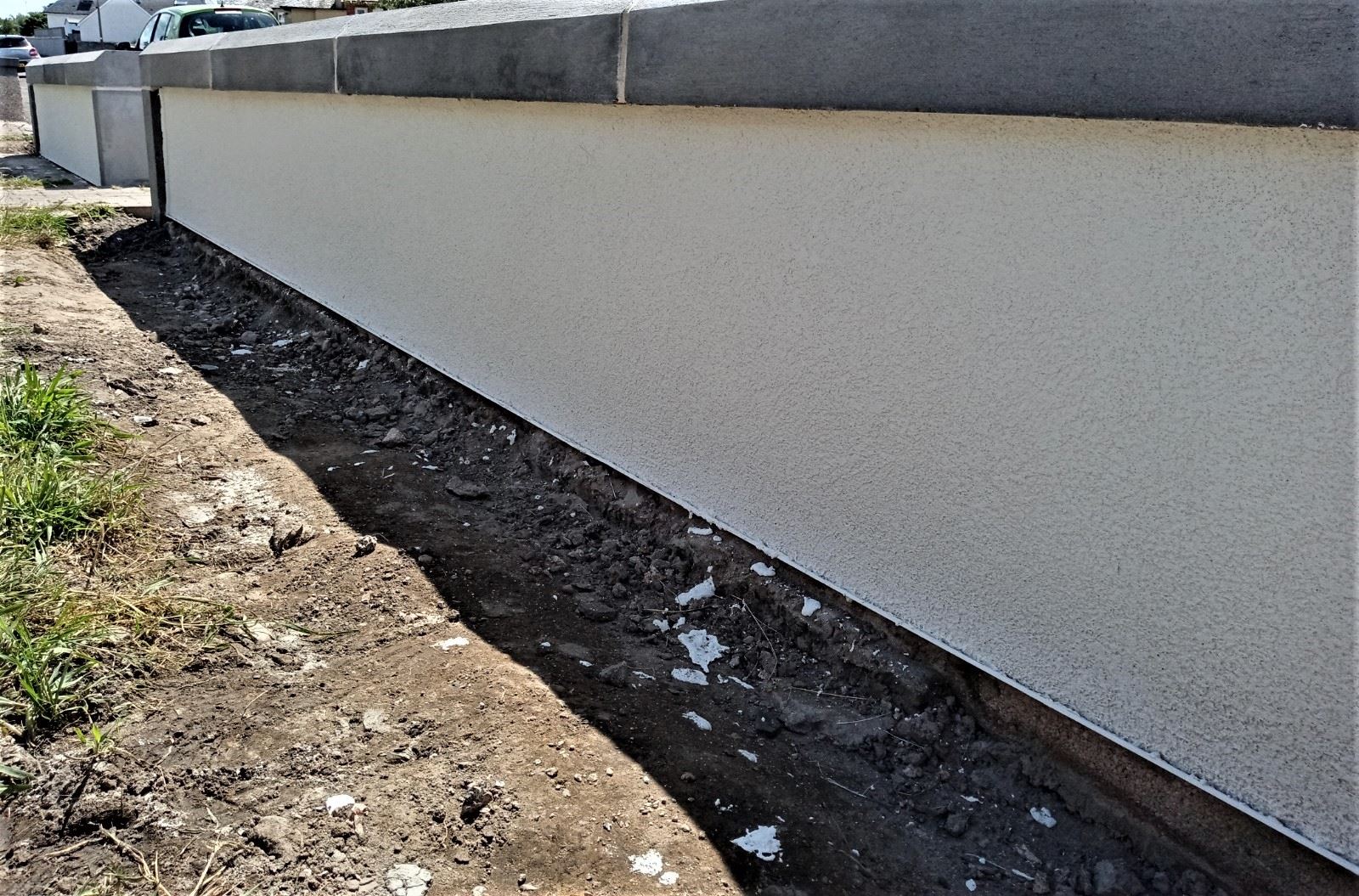 roughcast render repair on low boundary wall beside pathway