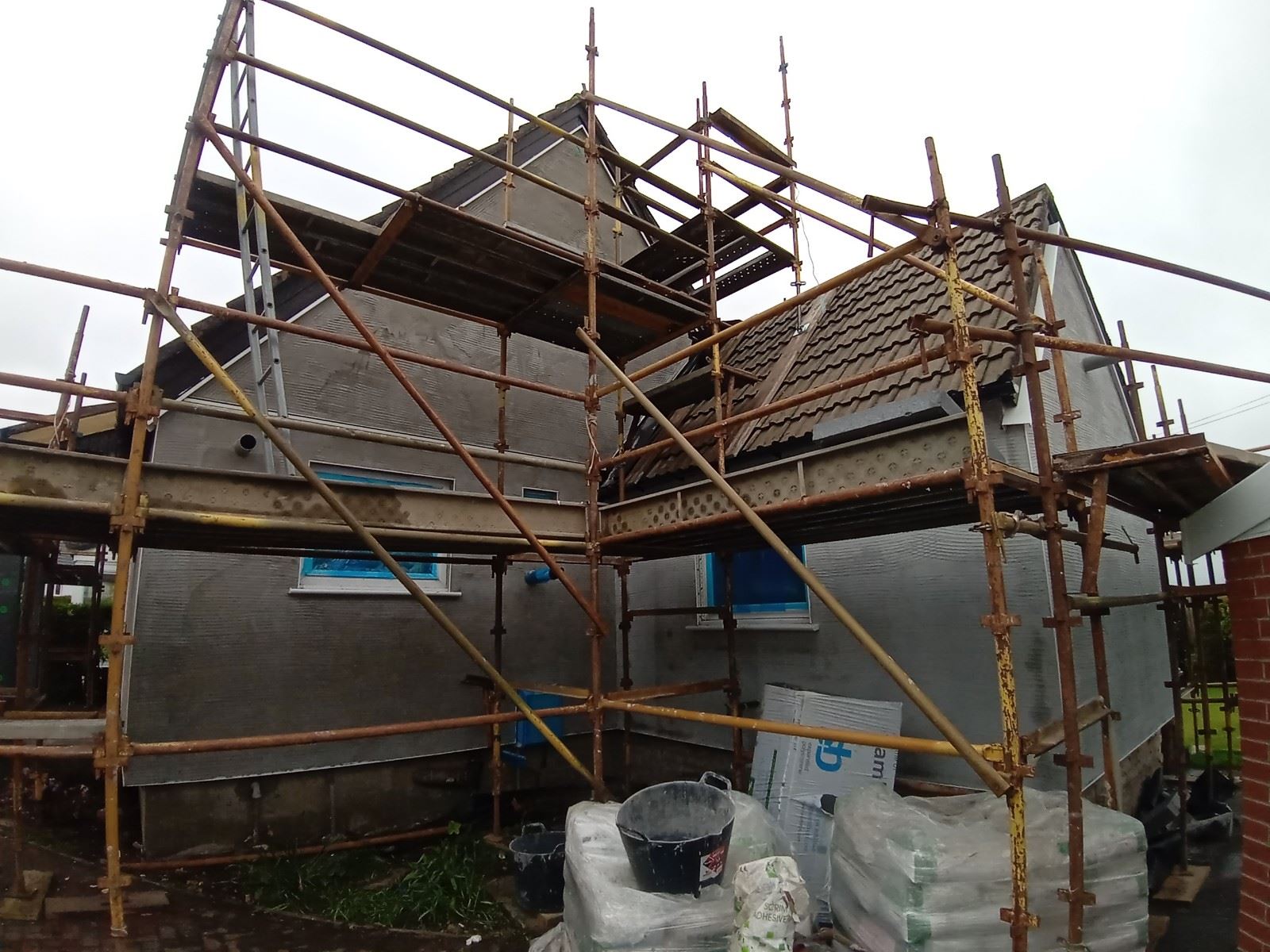 roughcaster Edinburgh working on gable wall with blue window covers