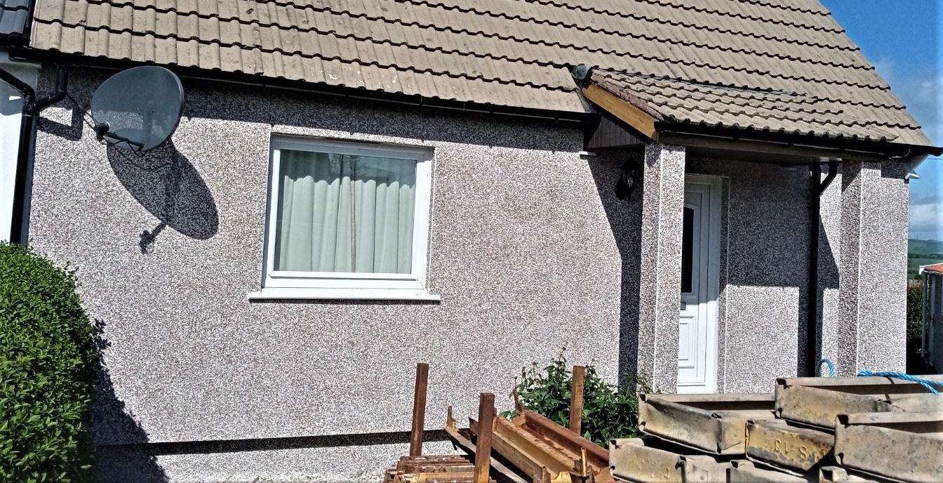 roughcast render repair on front wall with white framed window