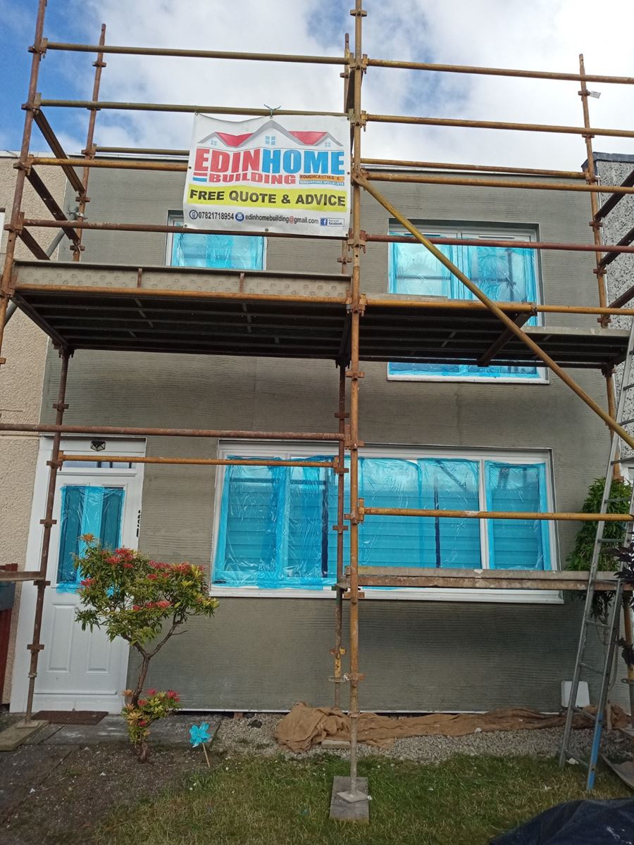 roughcast repair on house façade with scaffold and signage