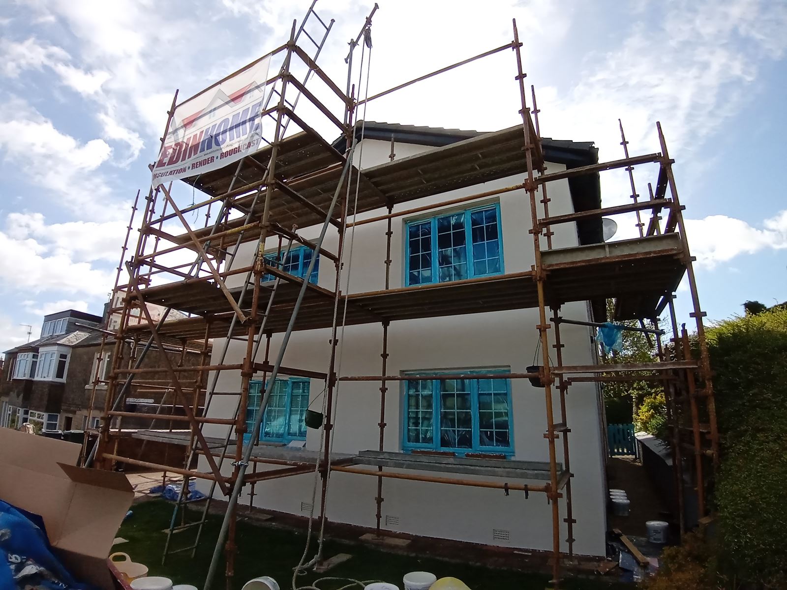 house rendering Edinburgh under scaffolding with blue-covered windows