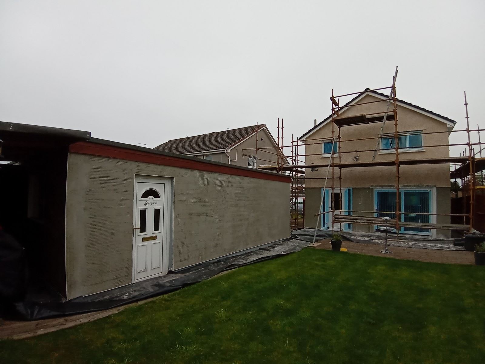 roughcast render repair on side wall with white entrance door