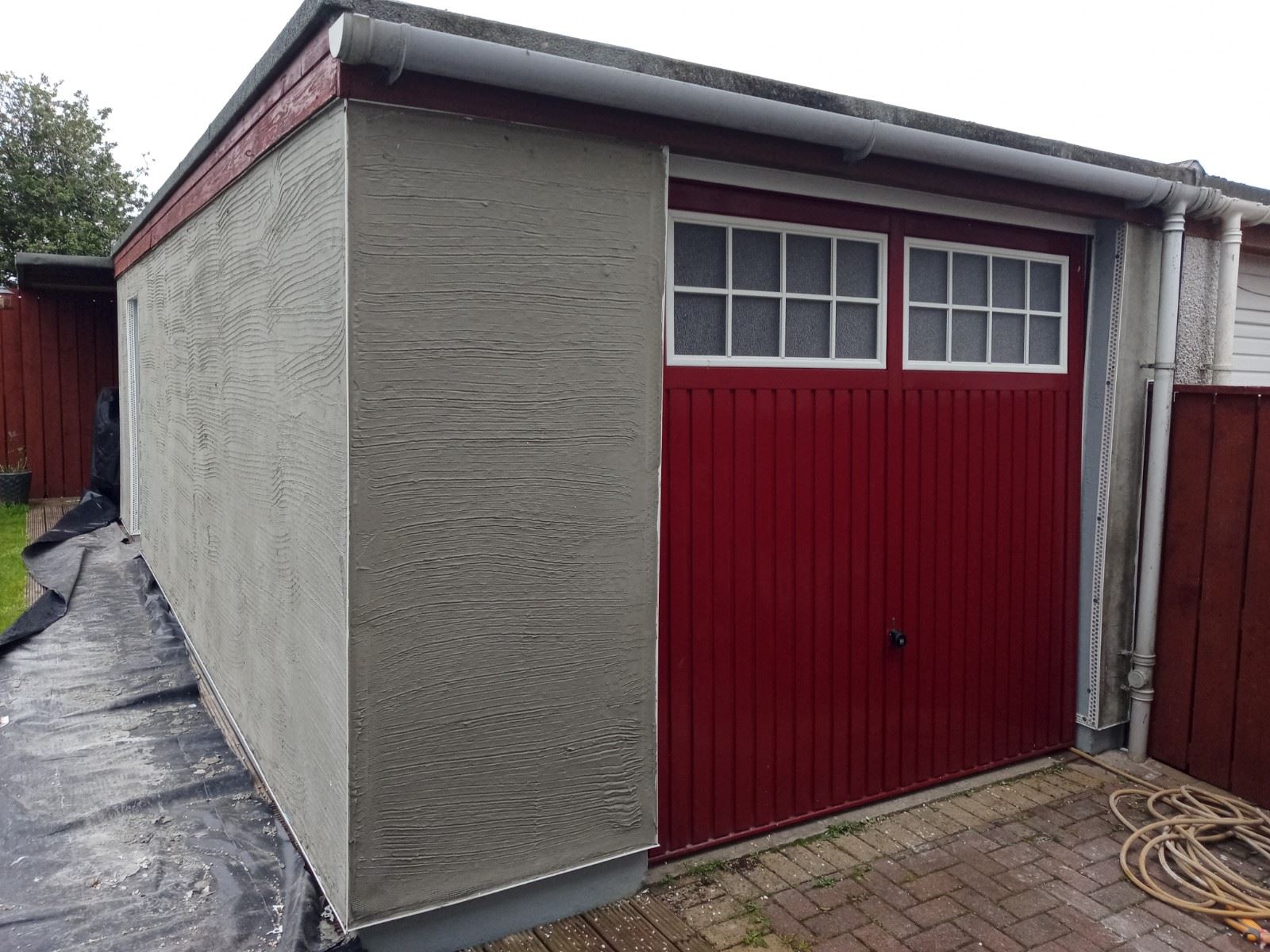 roughcaster Edinburgh working on garage wall with red door finish