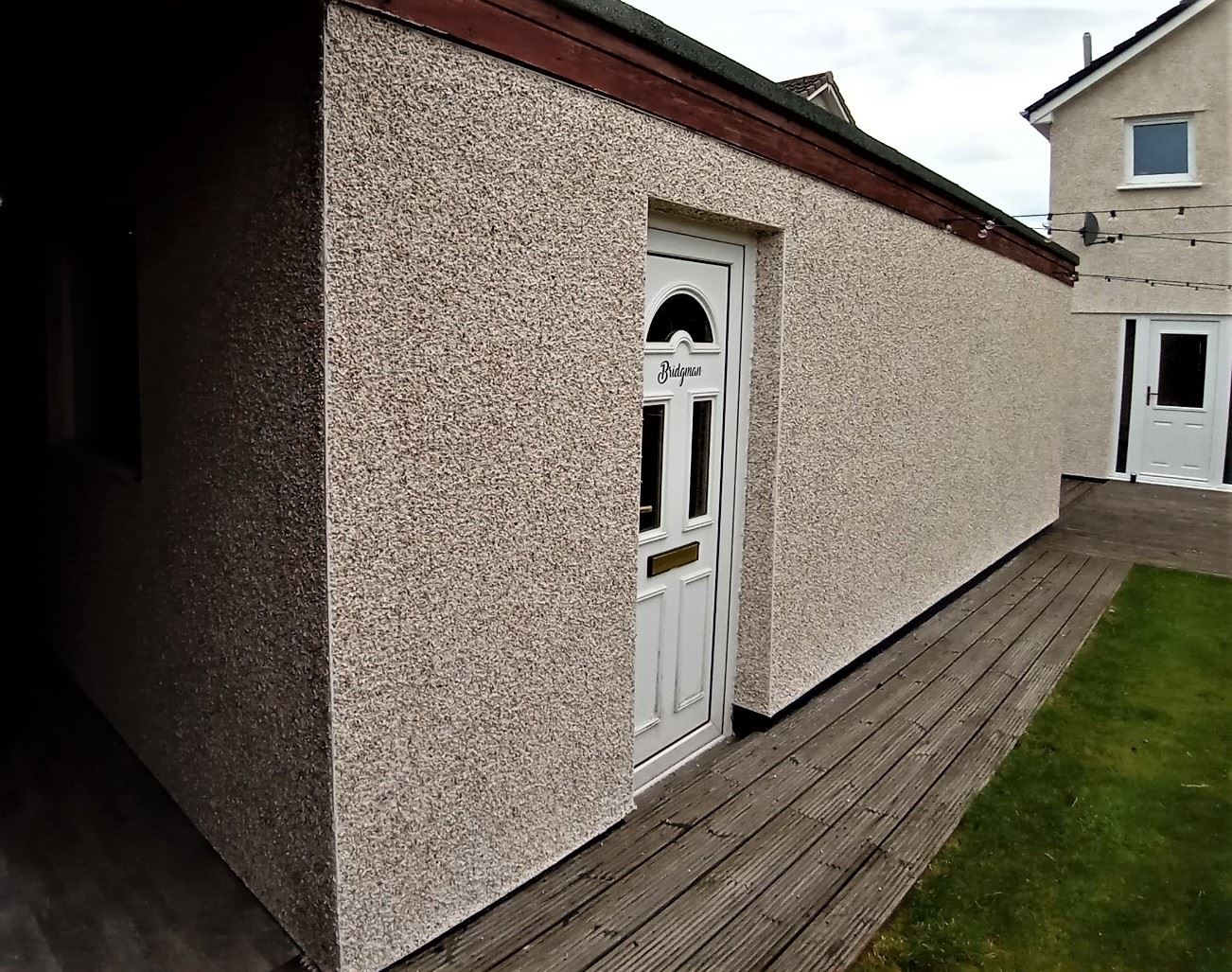 roughcast repair on side wall with white entrance door