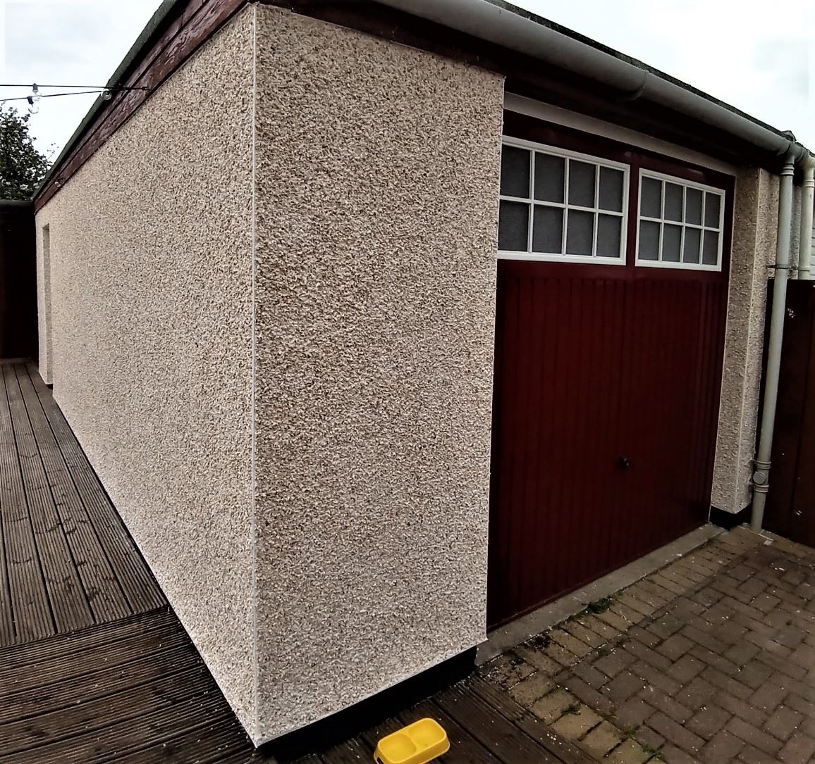 roughcast render repair on garage wall with red wooden door