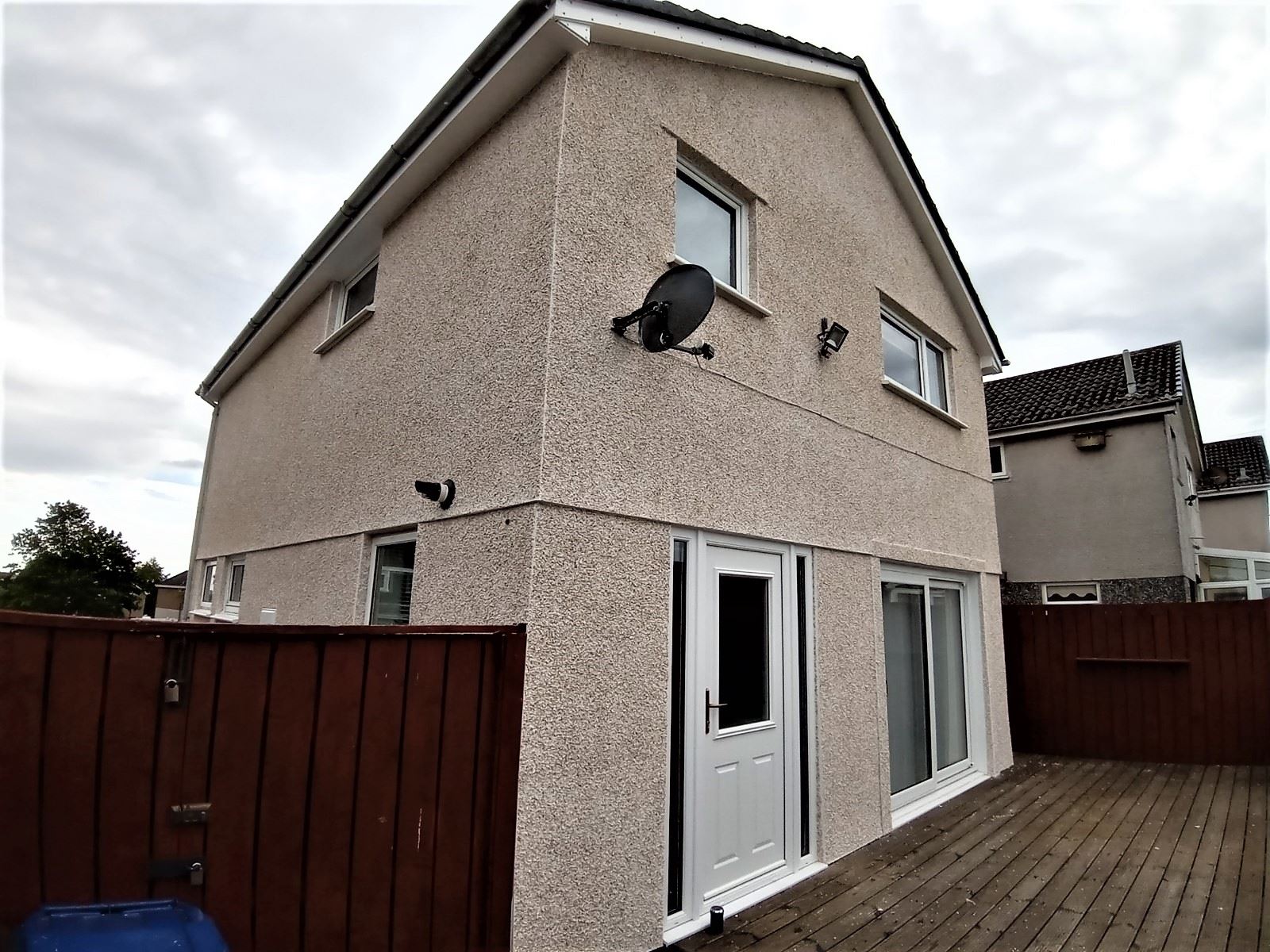 roughcaster Edinburgh applying render on two-storey wall with patio doors