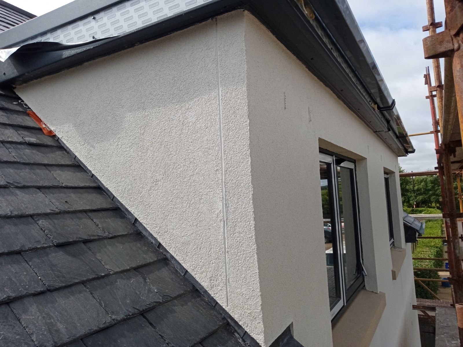 roughcast render repair completed on smooth white wall with window