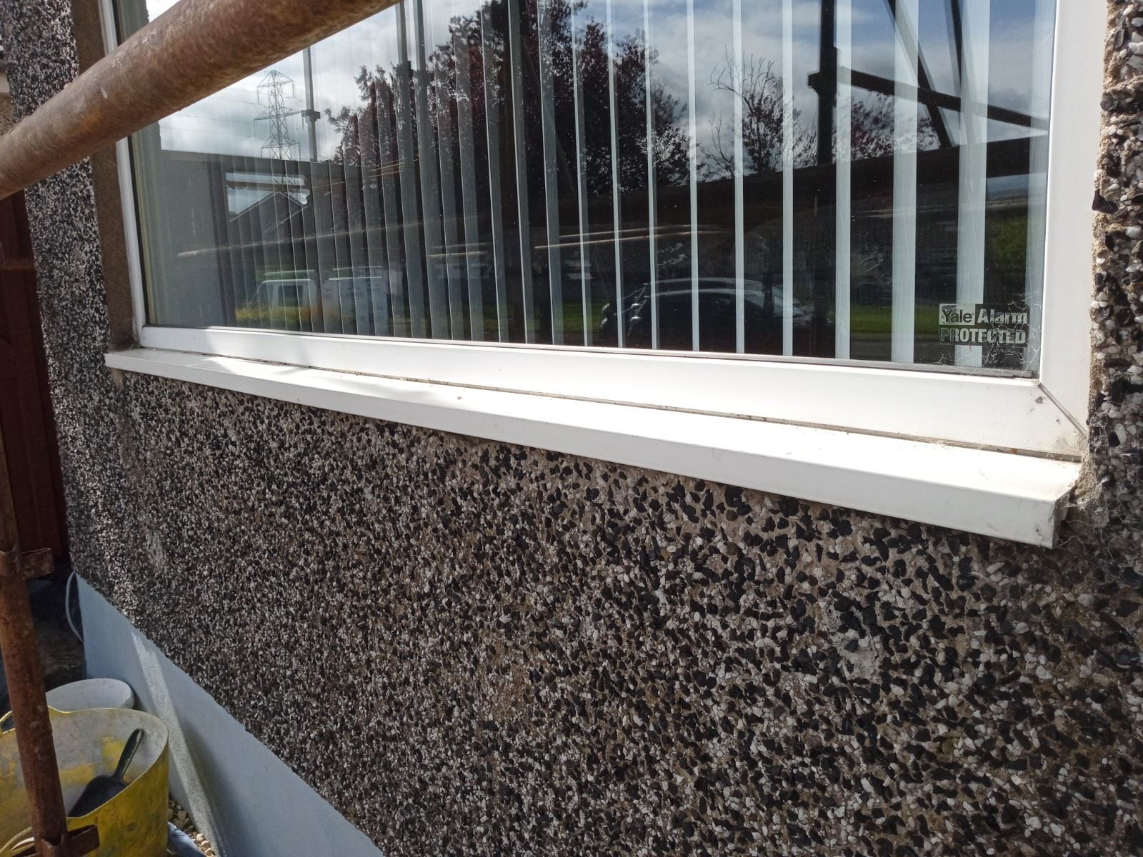 roughcast render Edinburgh on dark pebbledash wall beside window