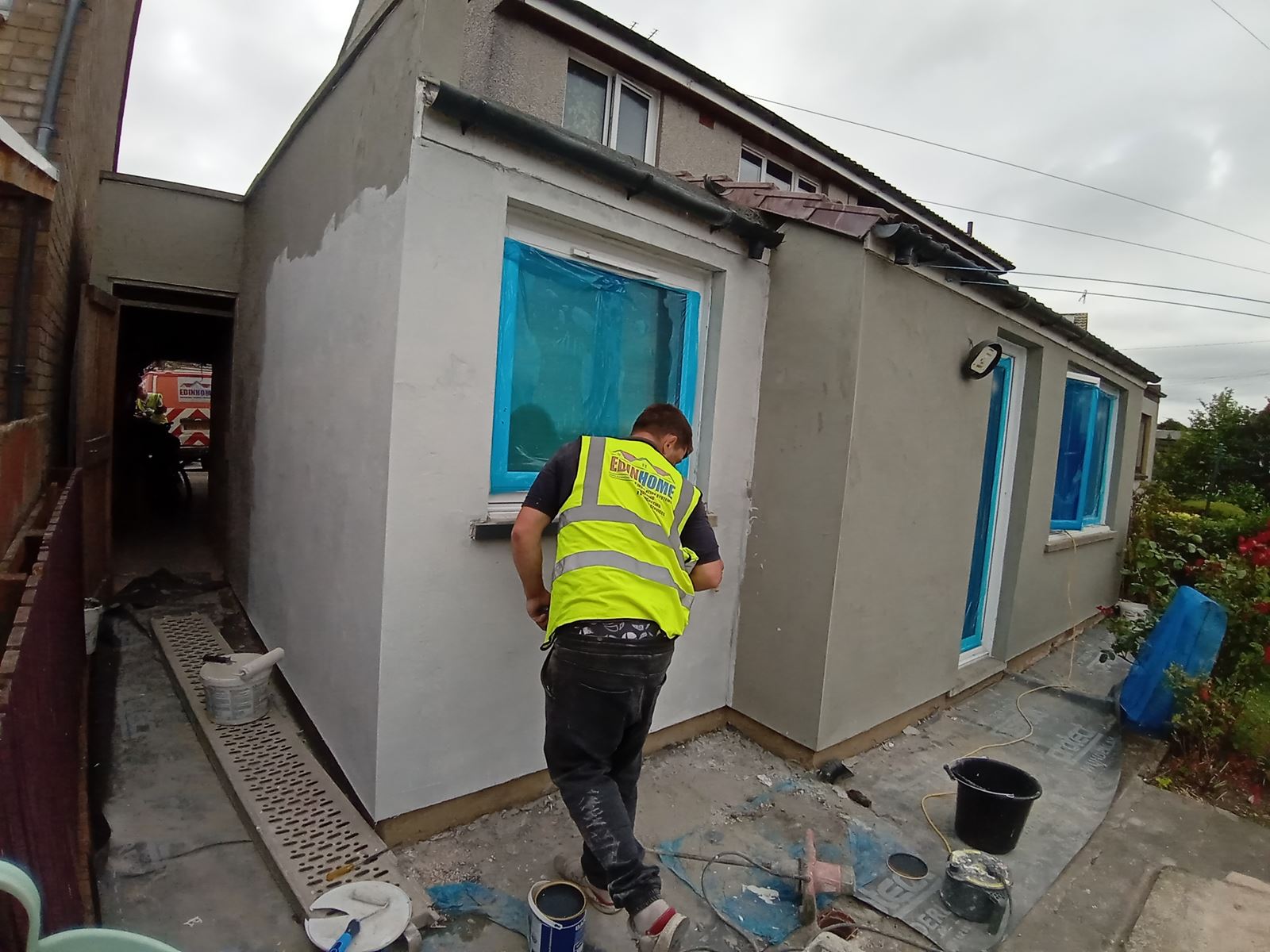 roughcast render repair on rear wall with blue-covered window