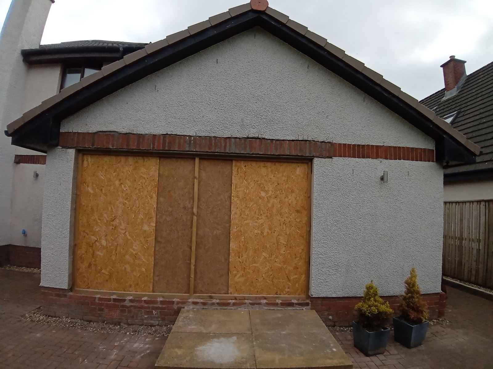 roughcast render repair on front wall with boarded-up windows