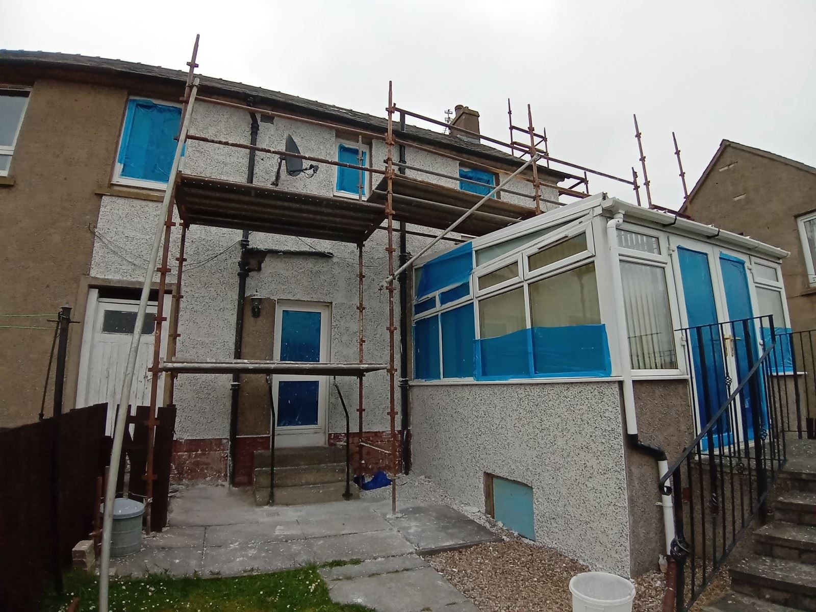 roughcast repair on rear wall with scaffold and window covers