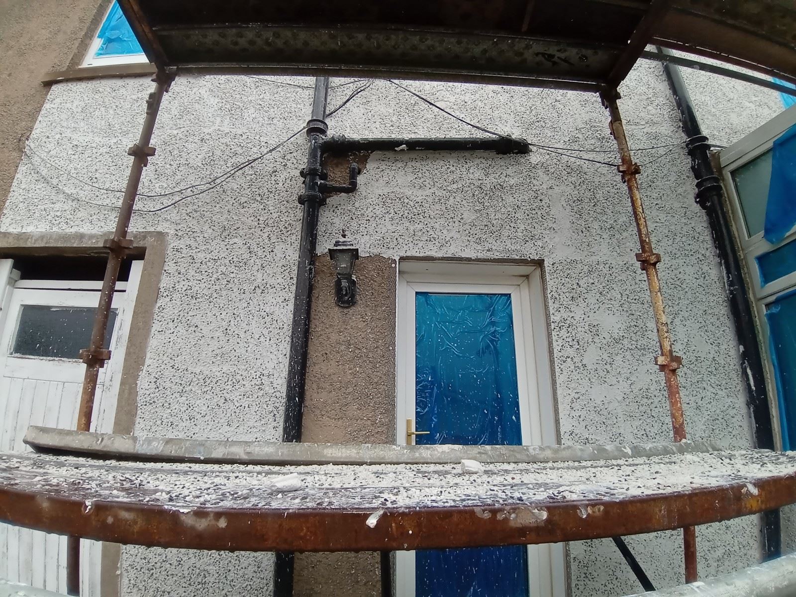 roughcast render repair around doorway with blue protective film