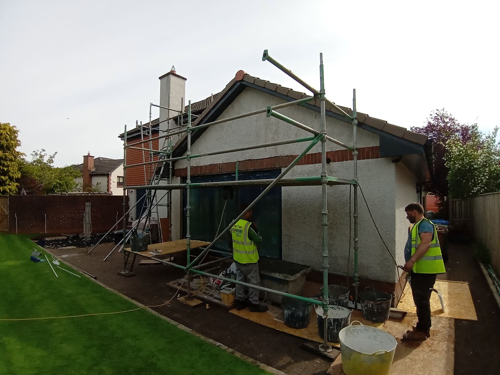 roughcasting Edinburgh on bungalow façade under scaffolding with workers
