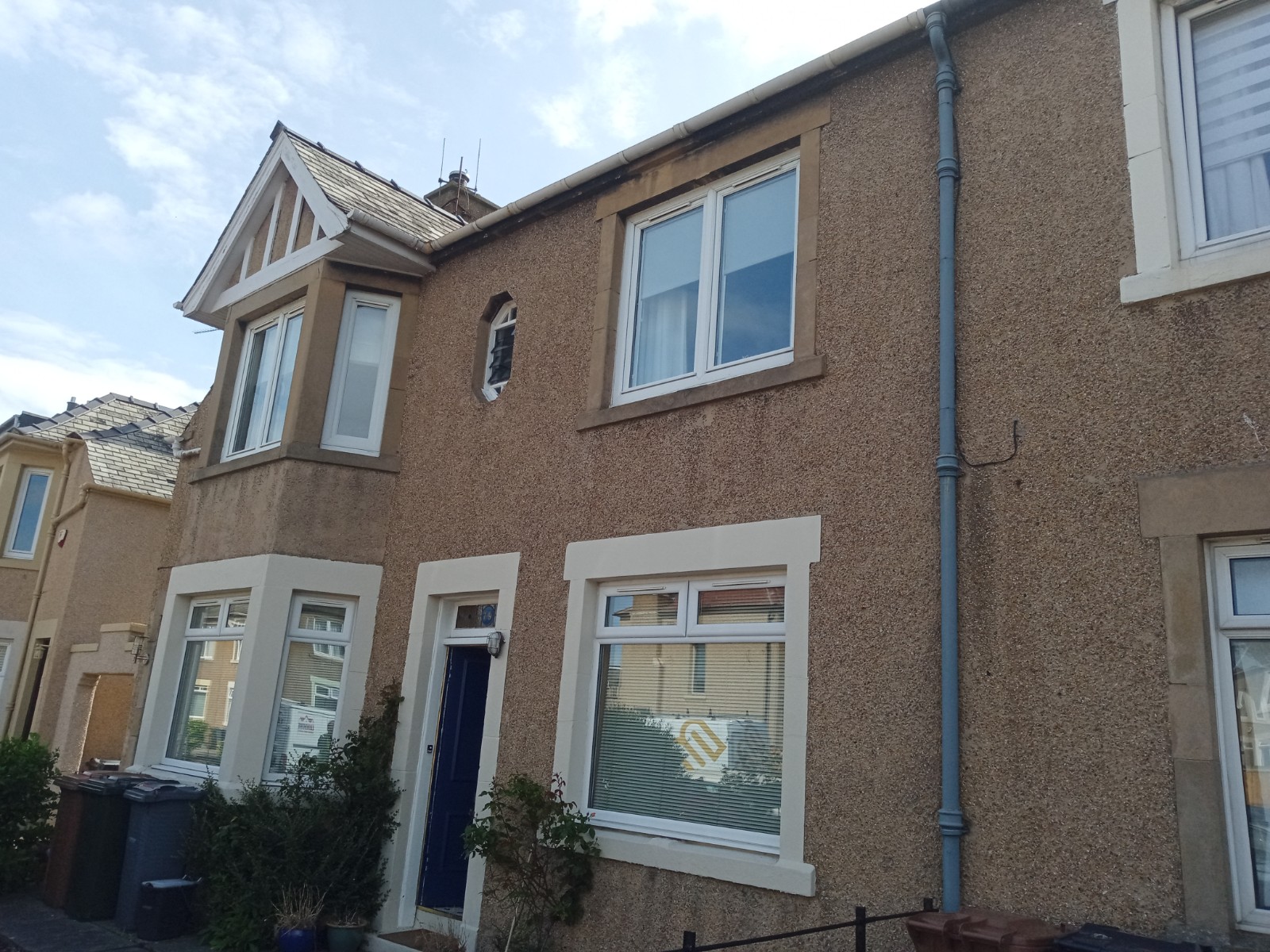 roughcast render repair on two-storey home with bay windows