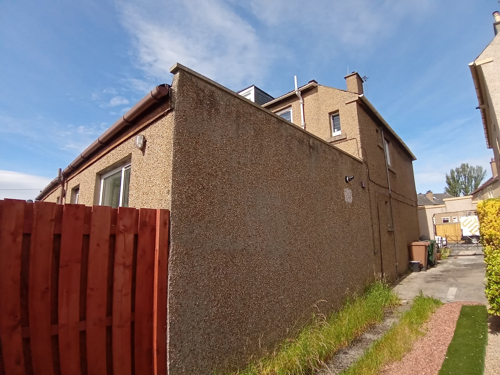 roughcasting Edinburgh on tall gable end wall beside red fence