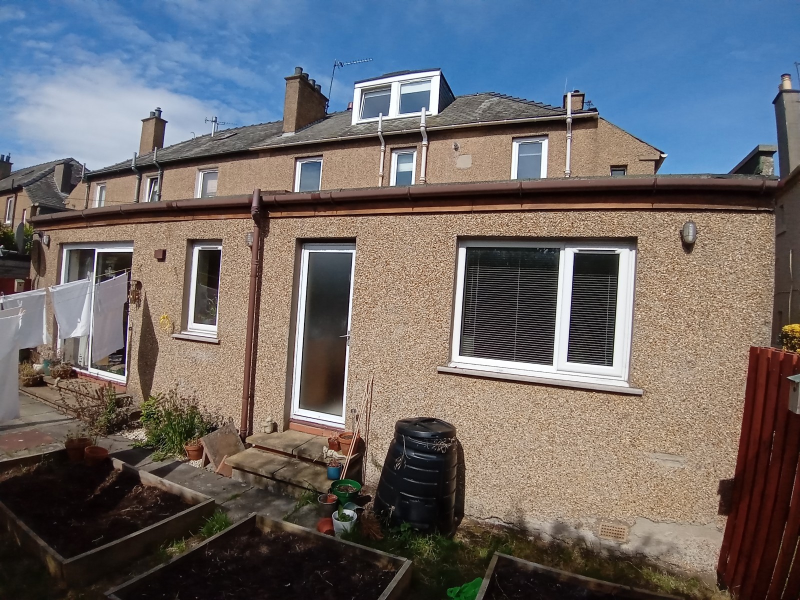 roughcast render repair on rear façade with white-framed windows