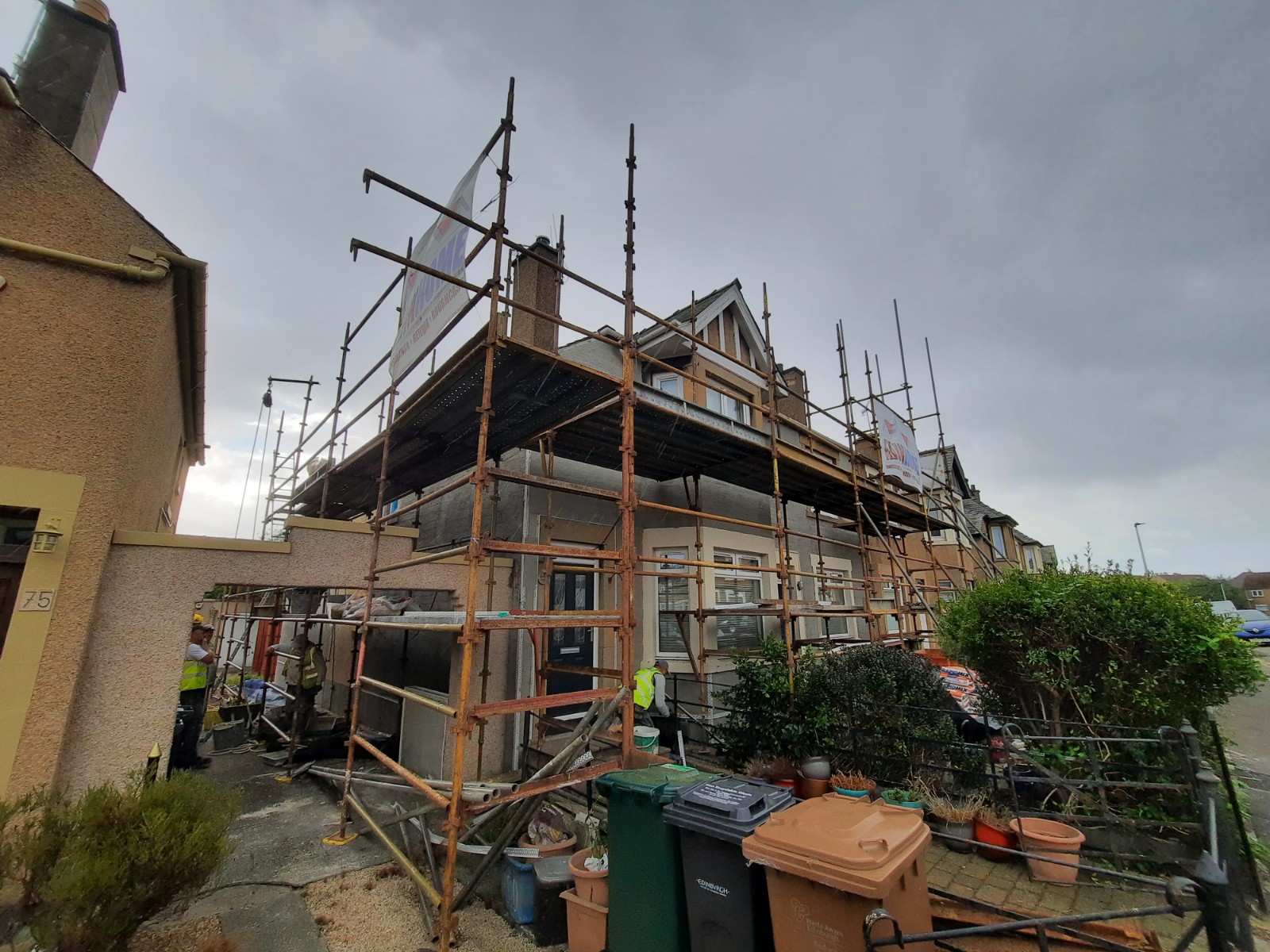 roughcast repair on multi-storey façade under scaffold with banner