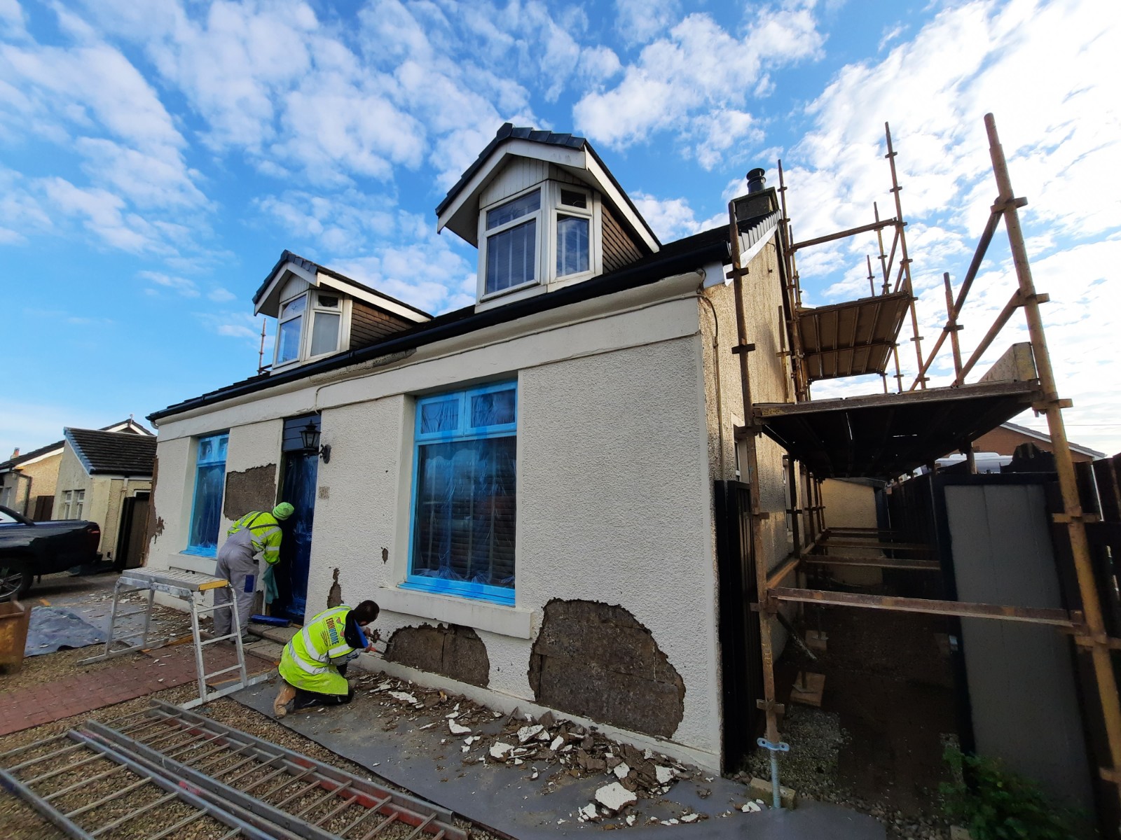 roughcaster Edinburgh applying fresh render coat beside blue window film