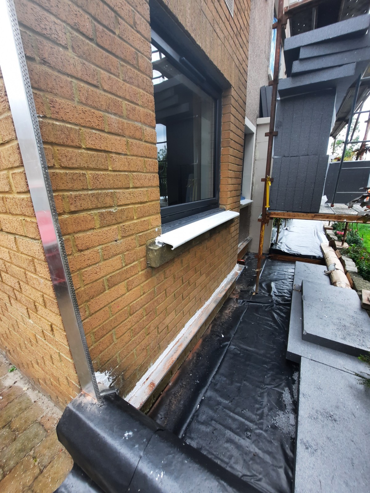 roughcast repair on brick wall with black-framed windows