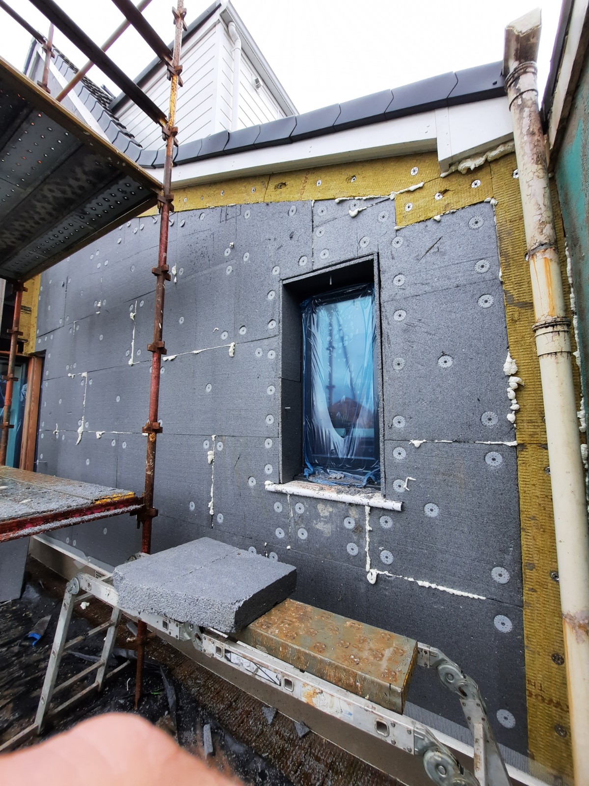 roughcasting Edinburgh on wall with insulation boards and blue-covered window