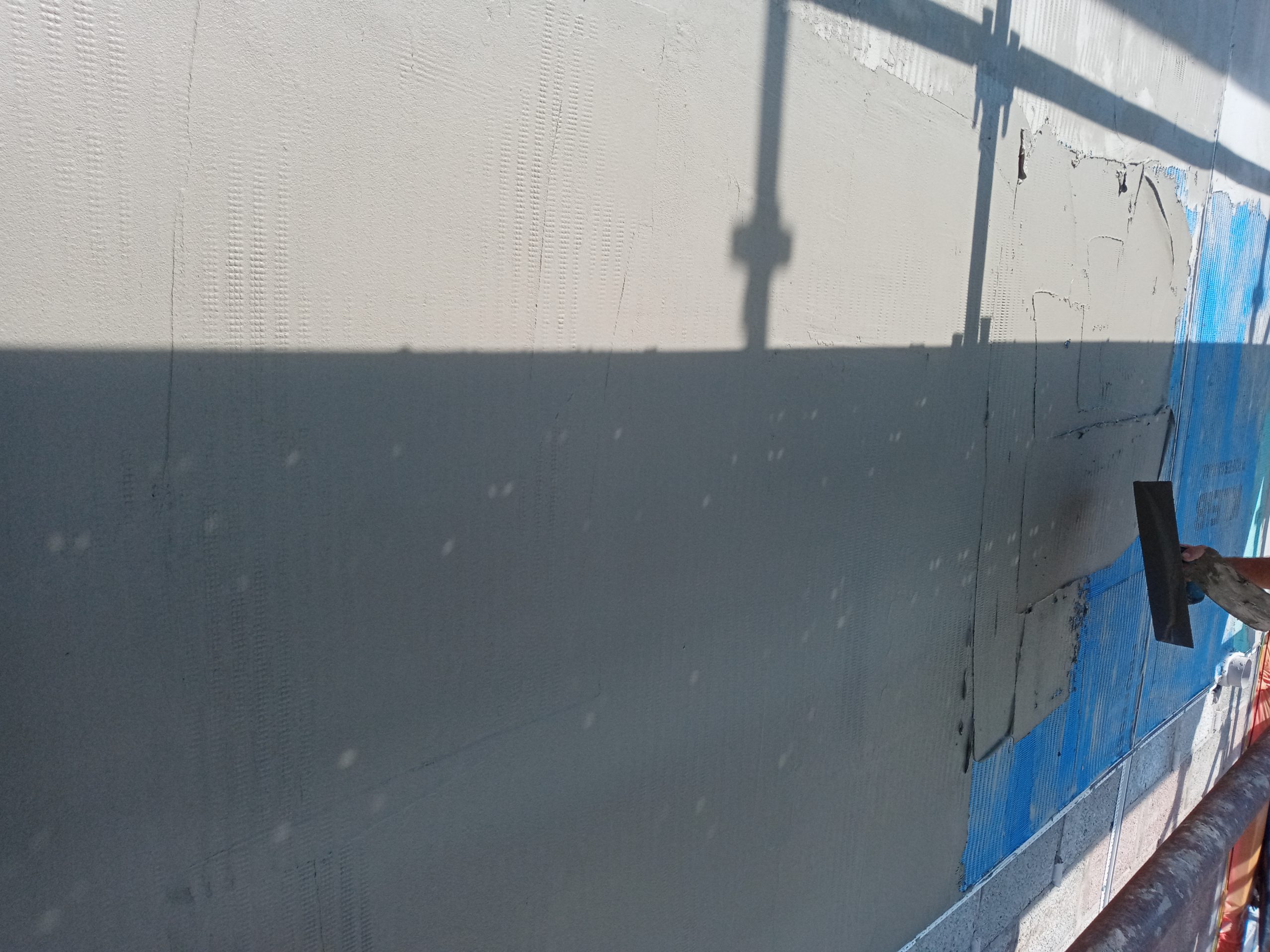 roughcast render repair on grey external wall close-up