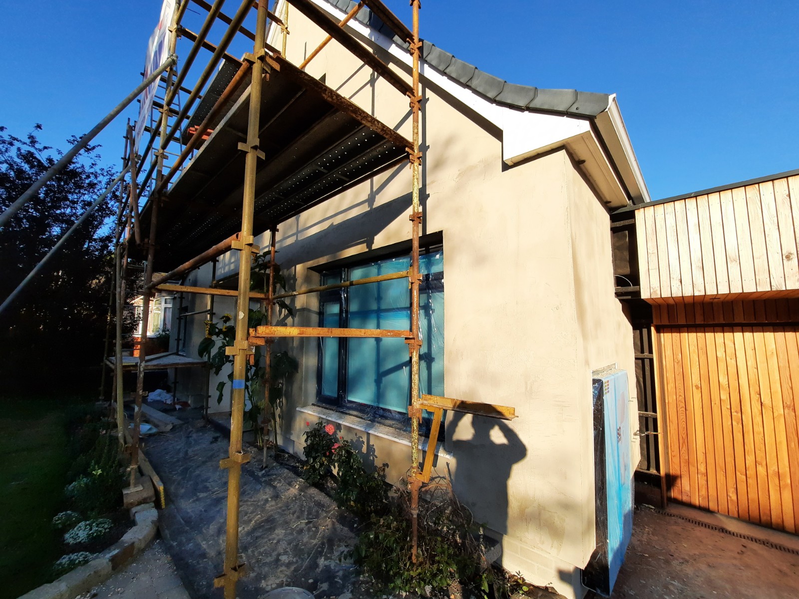 roughcast render Edinburgh applied around window under blue film