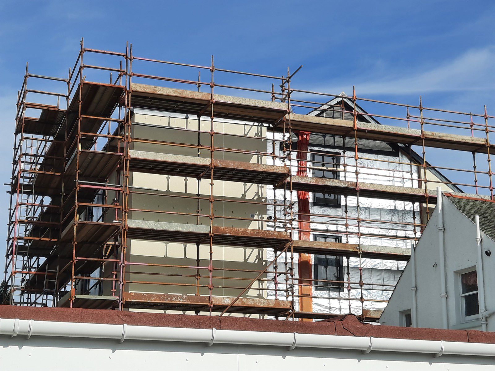 roughcast render repair on scaffolded property front
