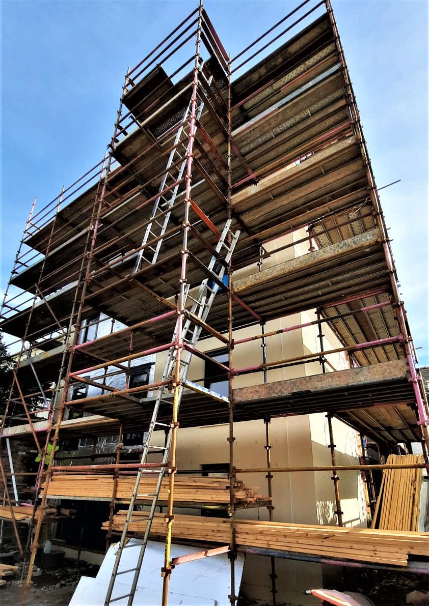 roughcast repair on large façade renovation under scaffold