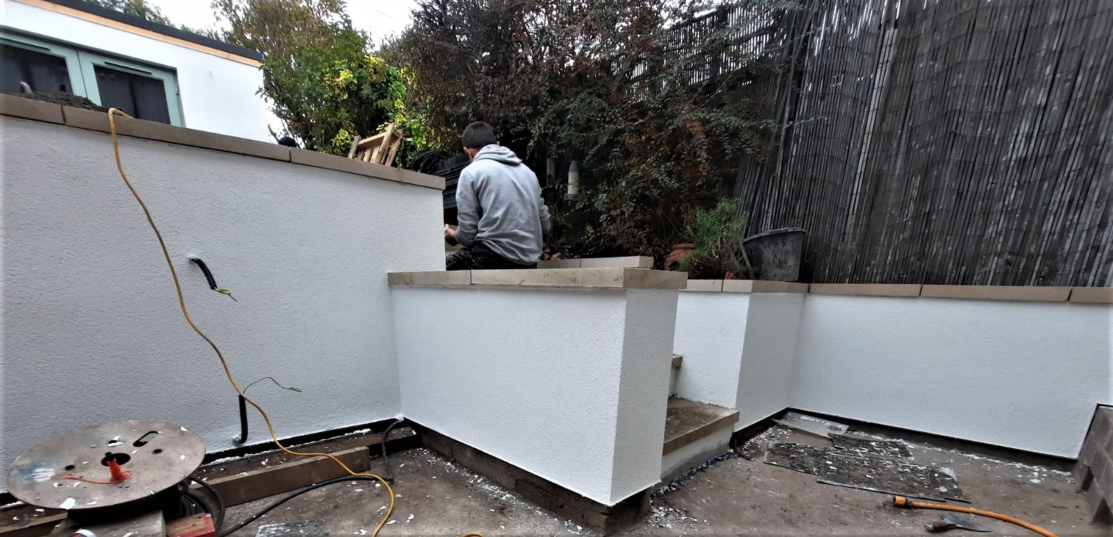 worker applying roughcasting Edinburgh on garden wall