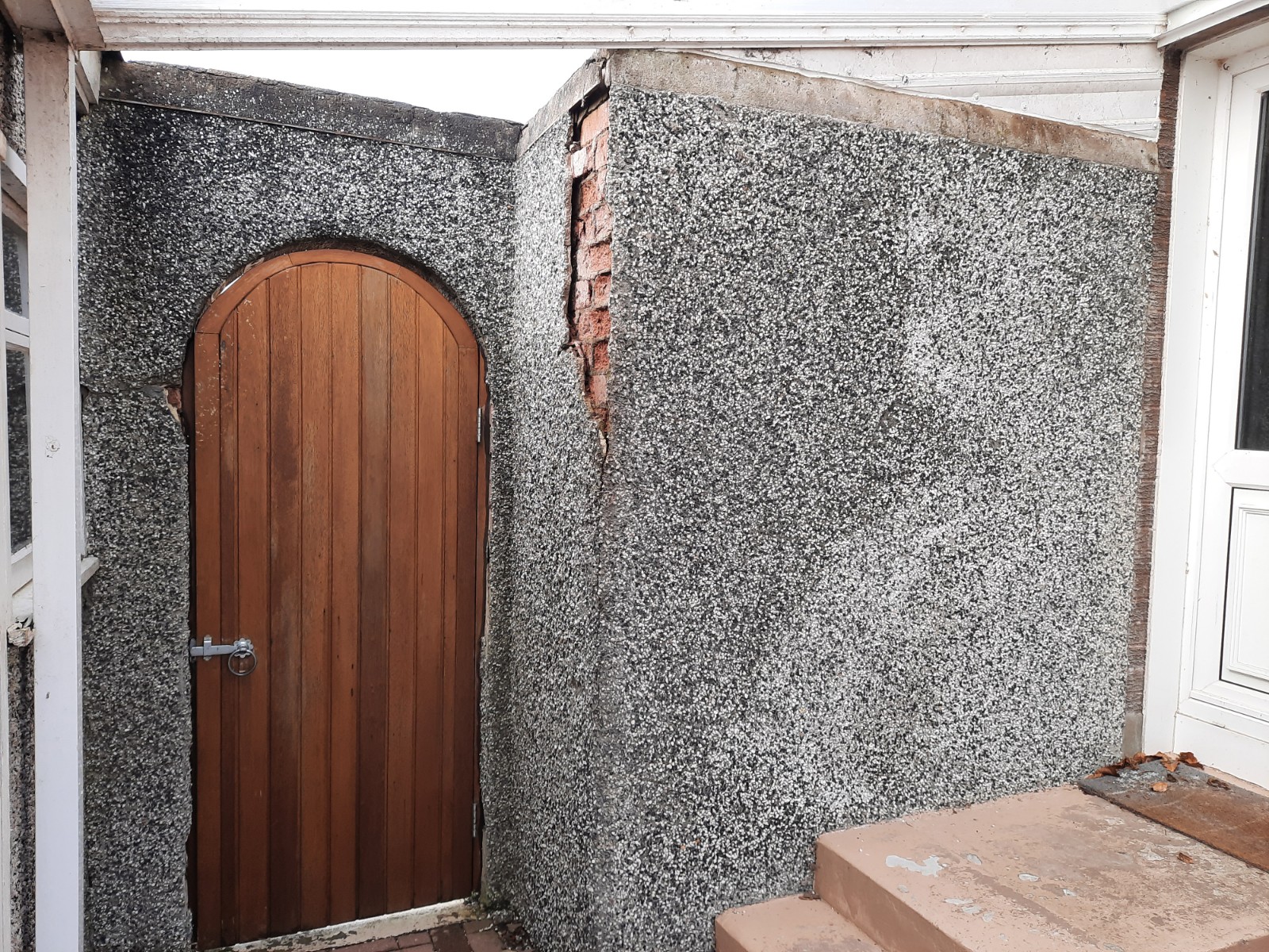 roughcast render Edinburgh repair on grey wall beside wooden gate