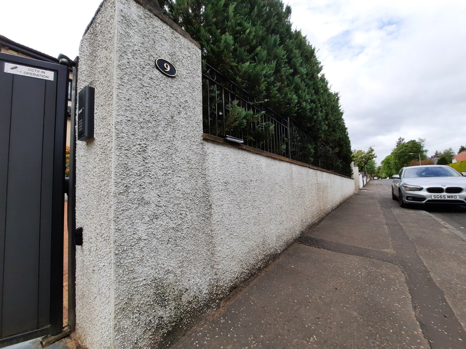 roughcast render repair on white finished wall beside driveway gate