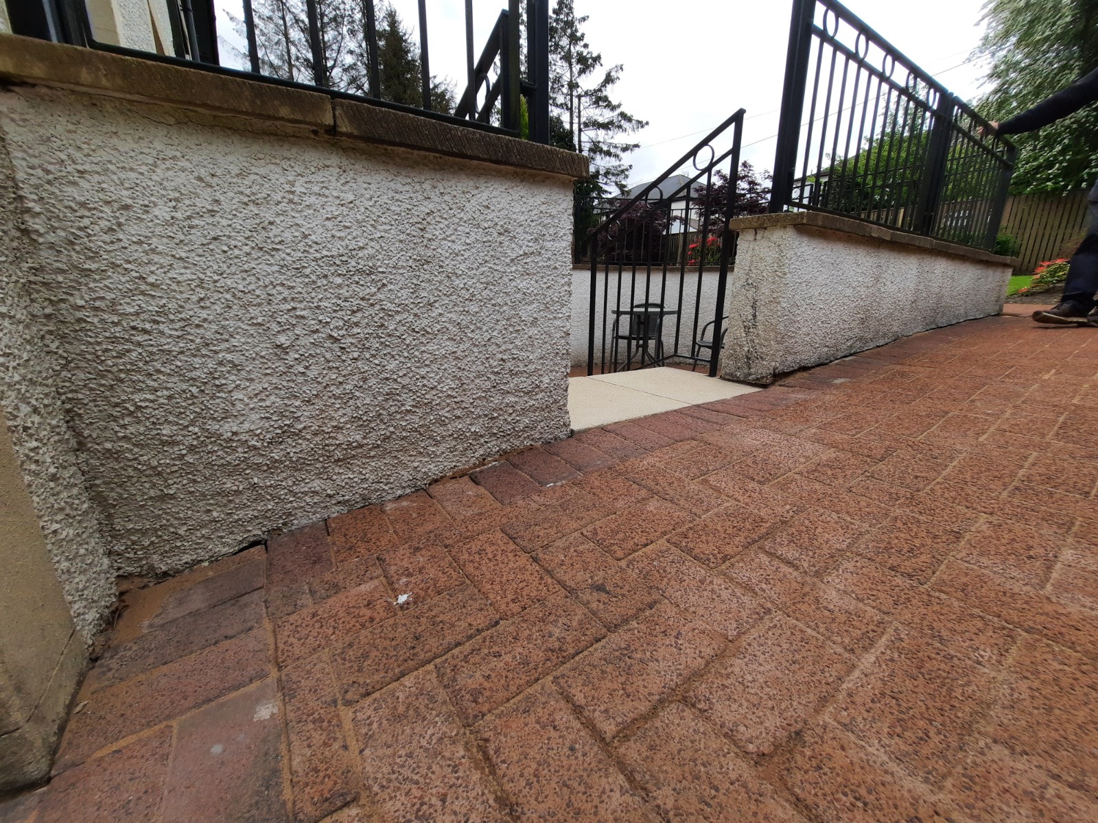 roughcast render repair on wall base beside paved driveway