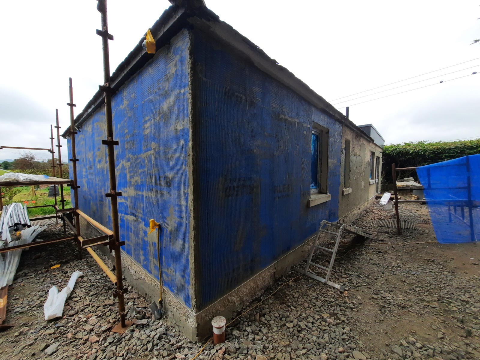roughcast render repair in progress on corner wall with scaffolding