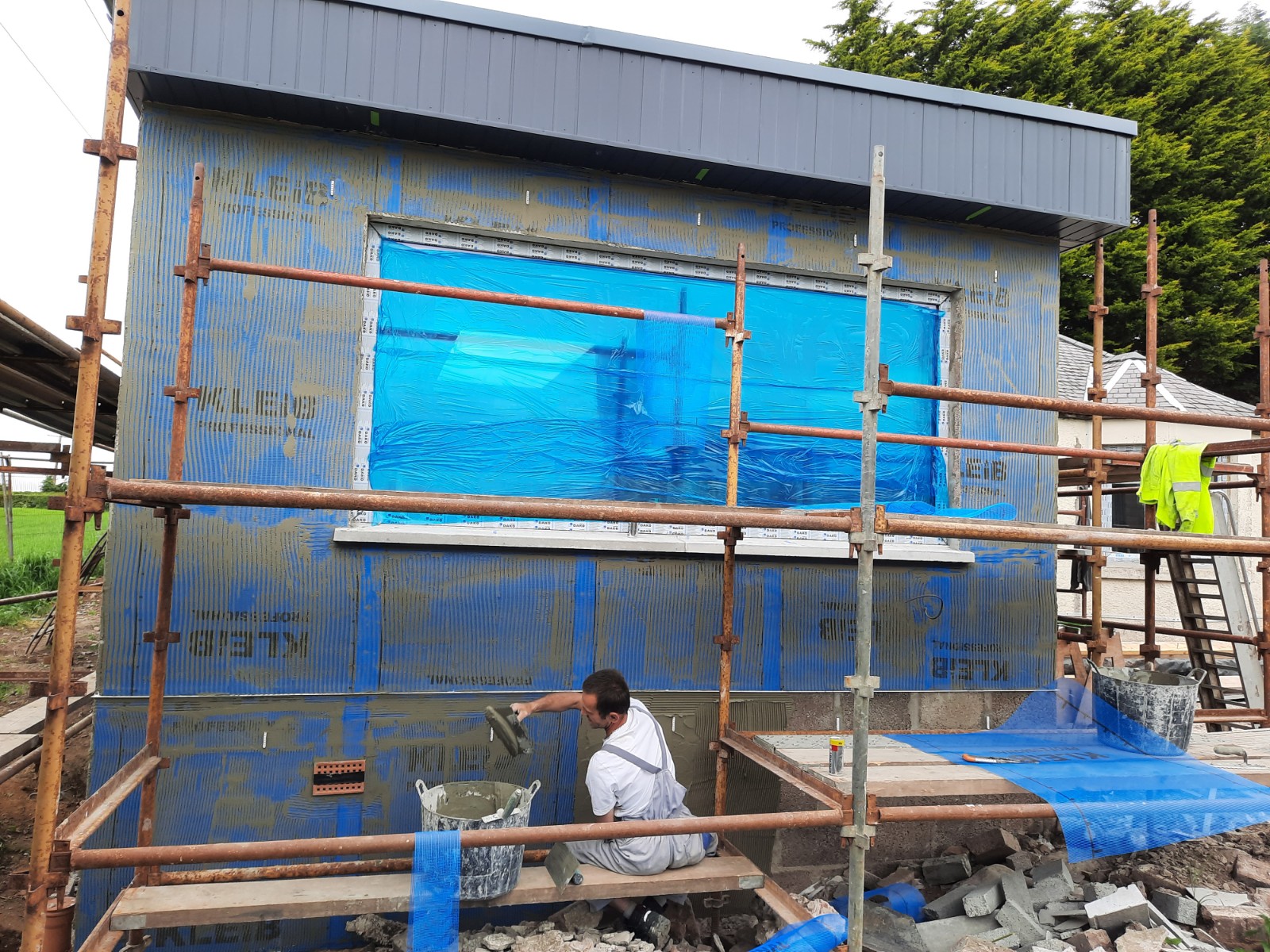roughcaster Edinburgh working on insulation-covered exterior wall