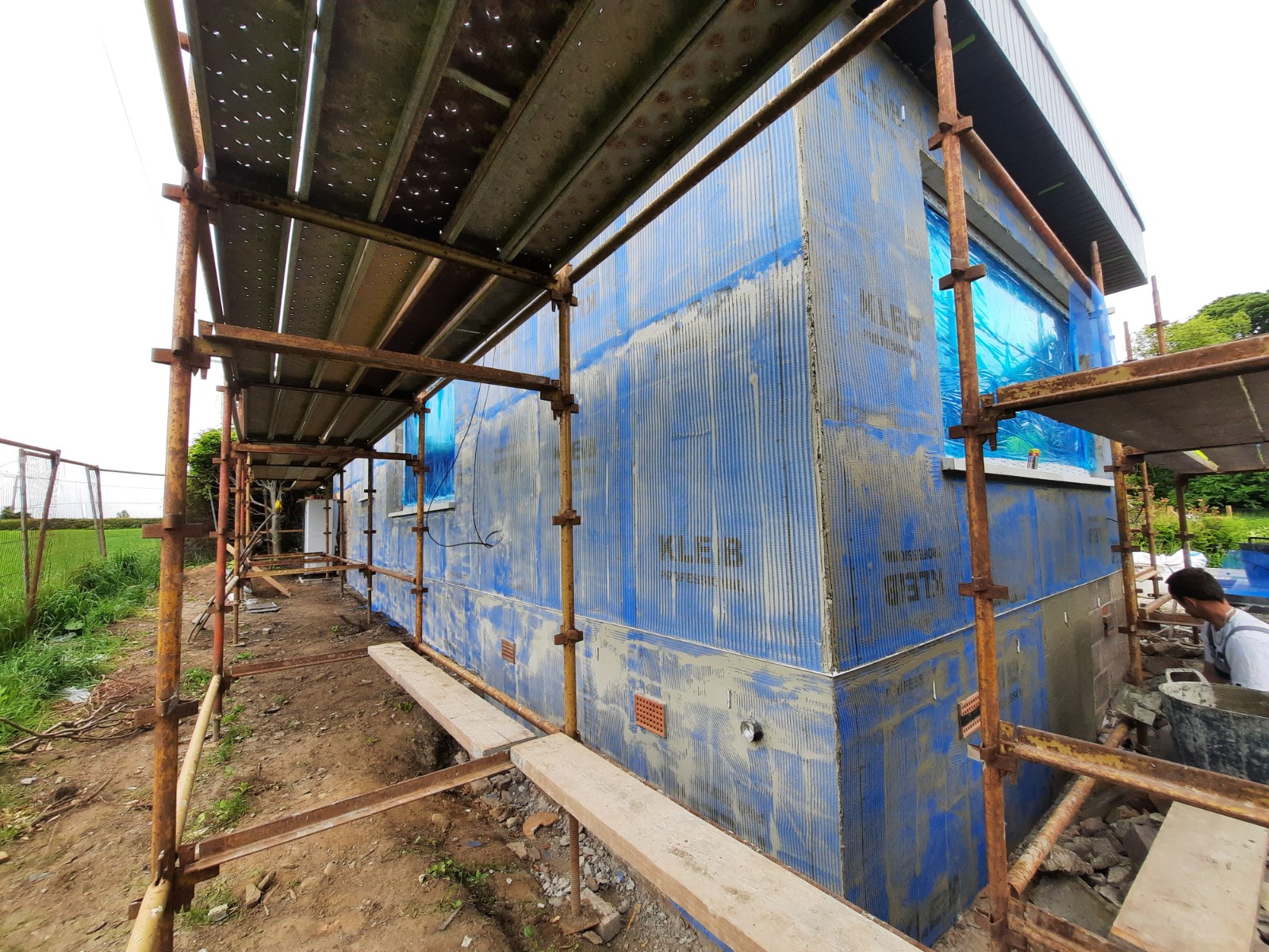 roughcast render Edinburgh on wall with blue-protected windows under scaffolding