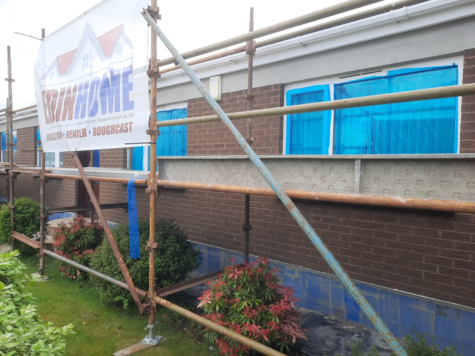 roughcast render Edinburgh under scaffolding beside garden area