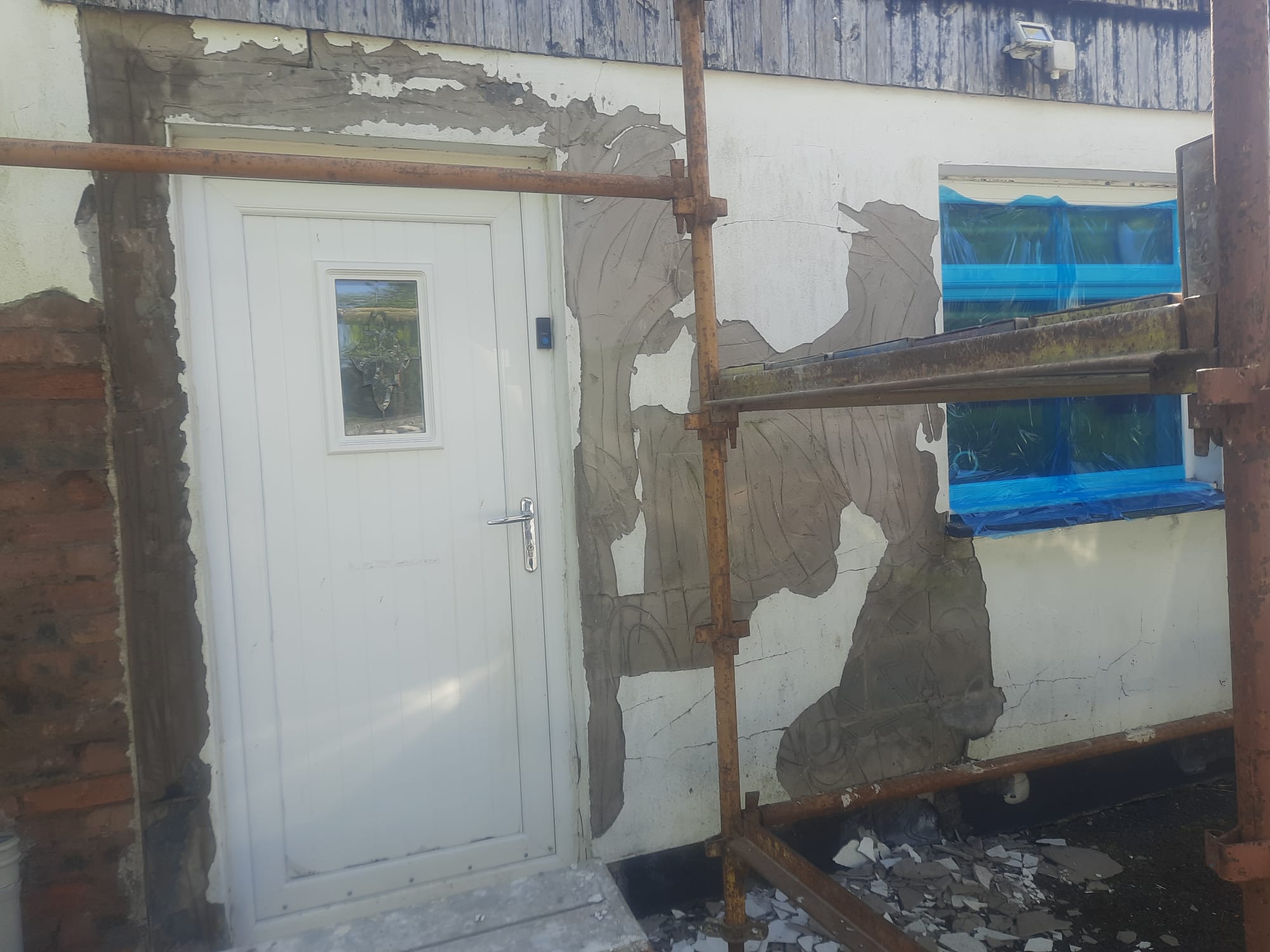 roughcasting Edinburgh repair in progress around white door under scaffolding
